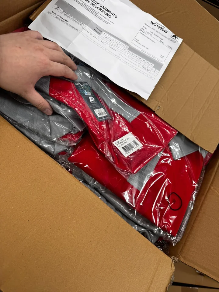 Printed polos being packed into a box with the packing slip
